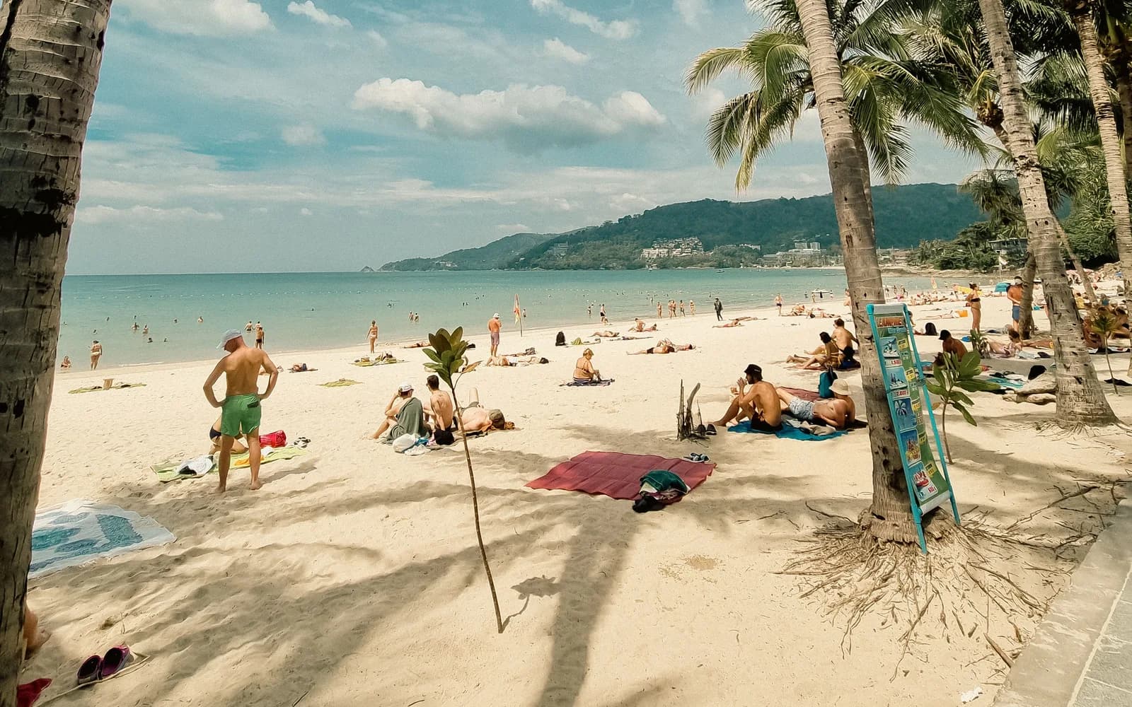 A sunny day on Patong Beach, Phuket, with palm trees and sunbathers