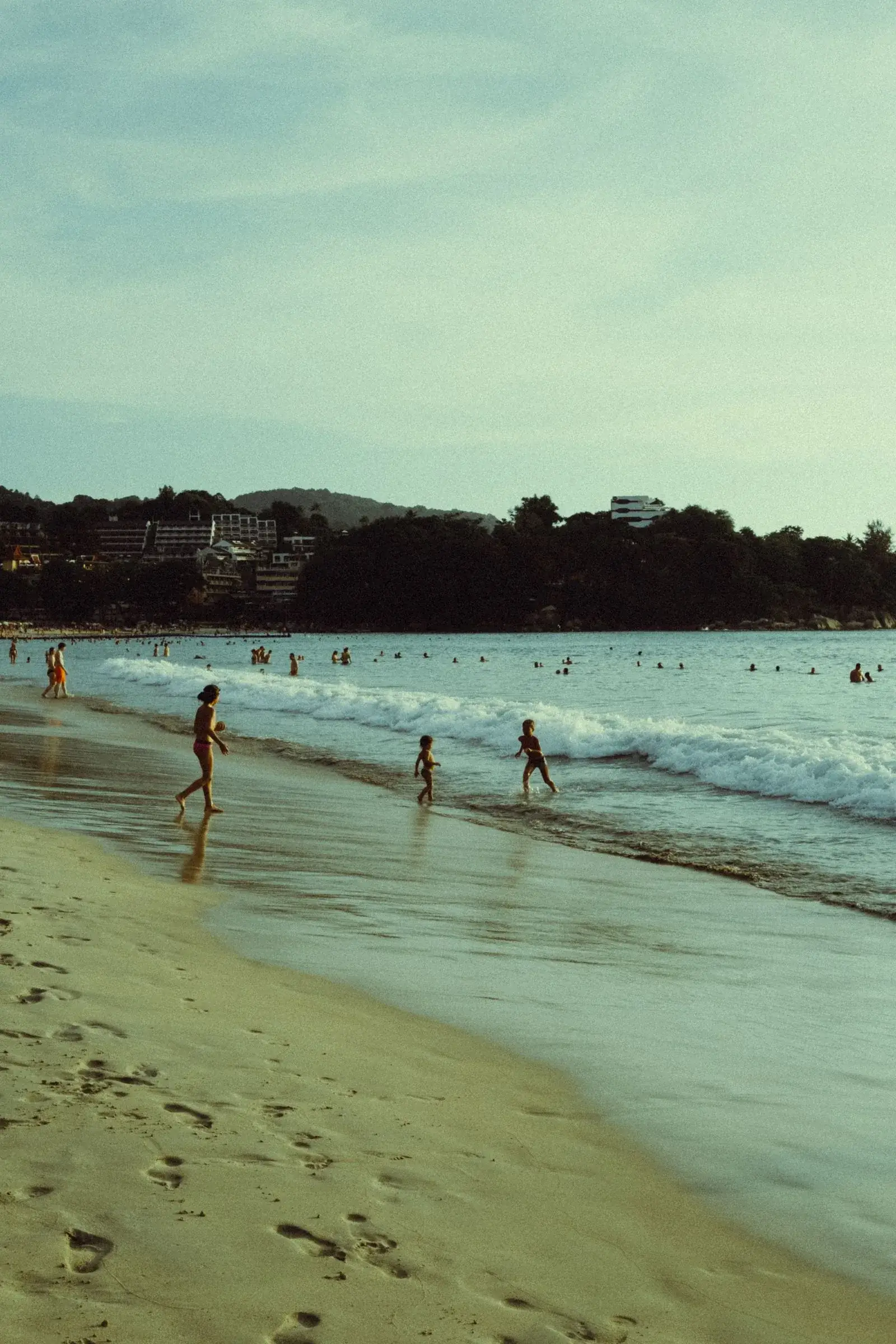 Sunbeds and people spread along a wide Phuket beach